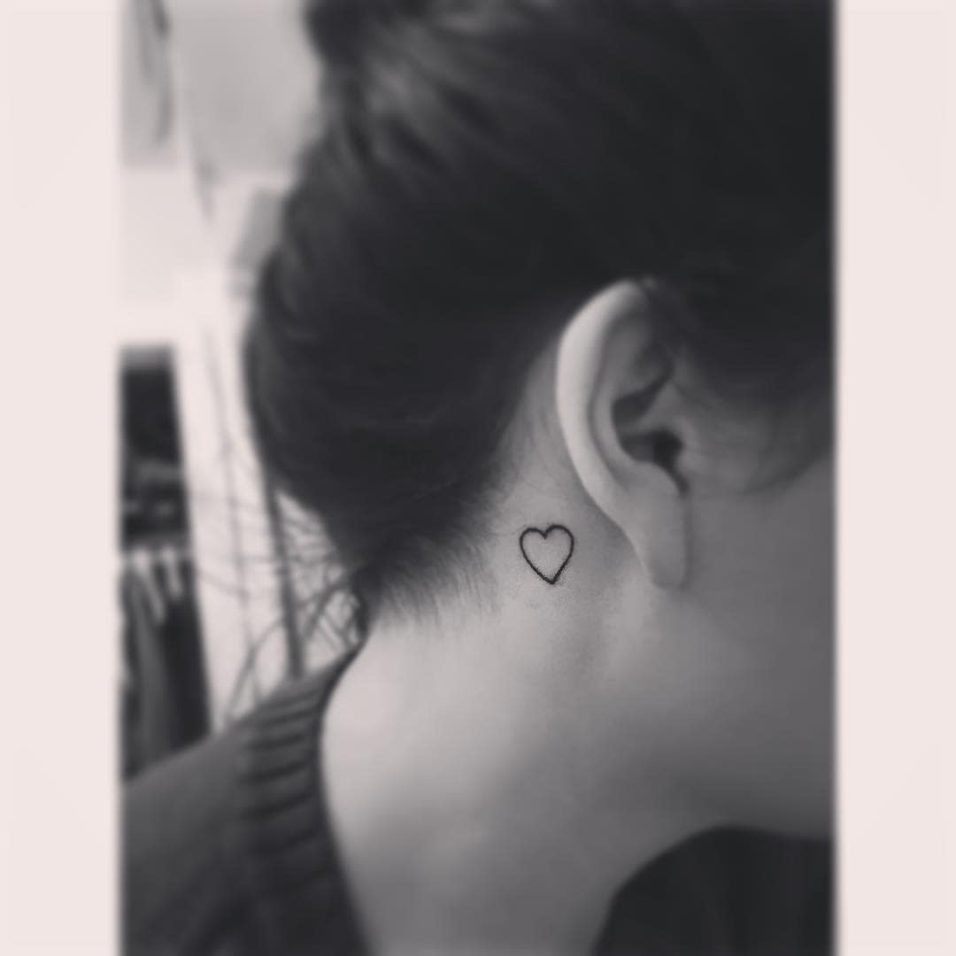 Small heart tattoo behind a woman's ear