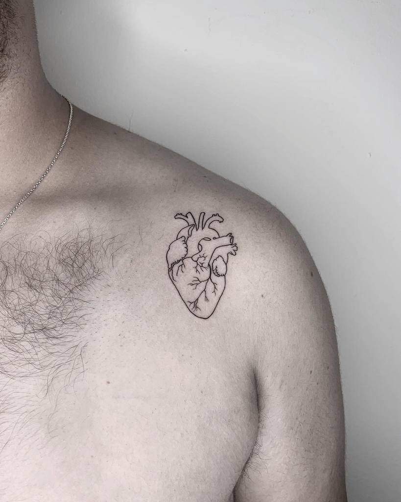 Outline tattoo of an anatomical heart on a person's shoulder near the collarbone