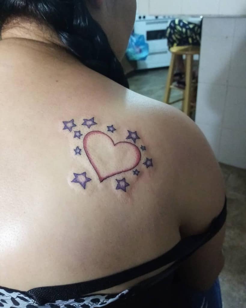 Tattoo of a heart surrounded by stars on an upper back