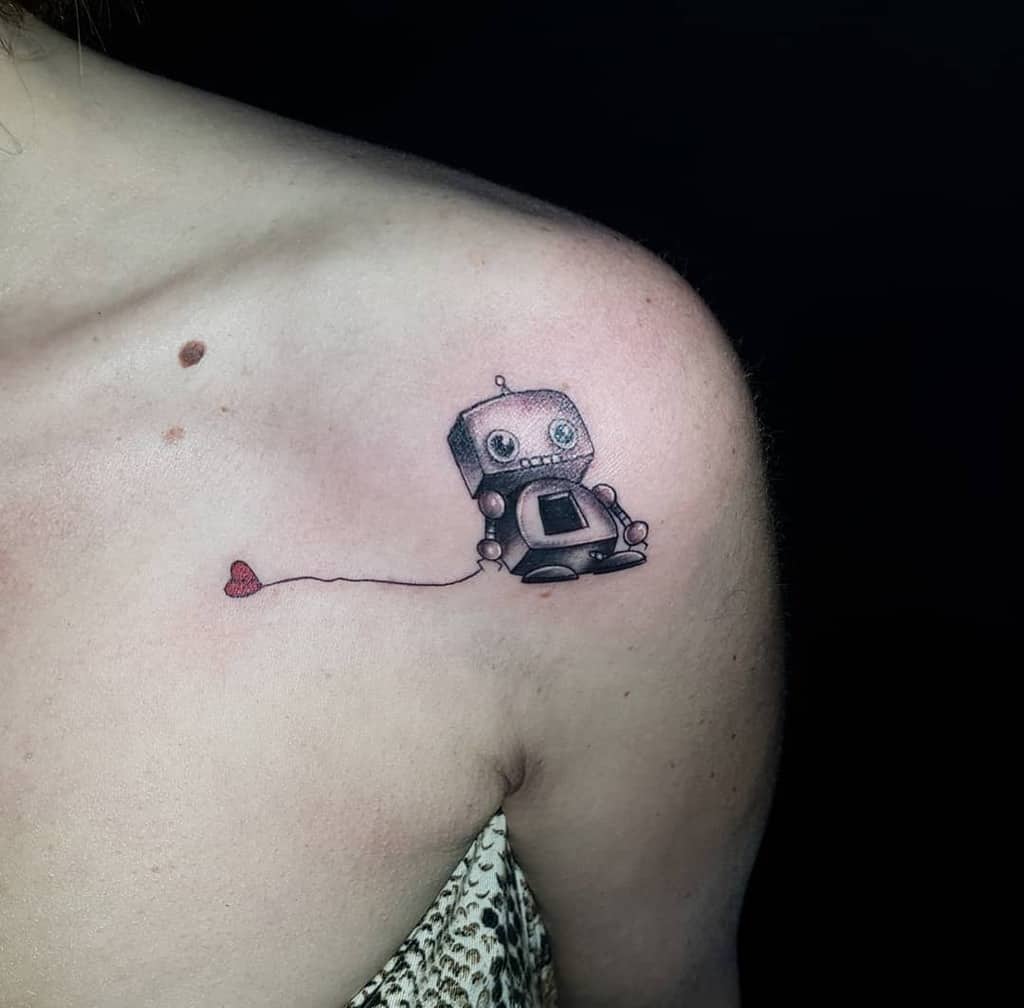 Tattoo of a cute robot holding a heart string on a shoulder