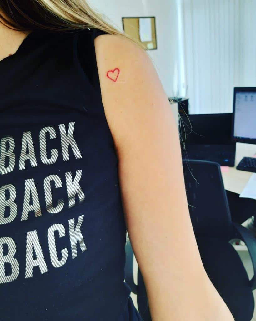 Small red heart tattoo on an upper arm