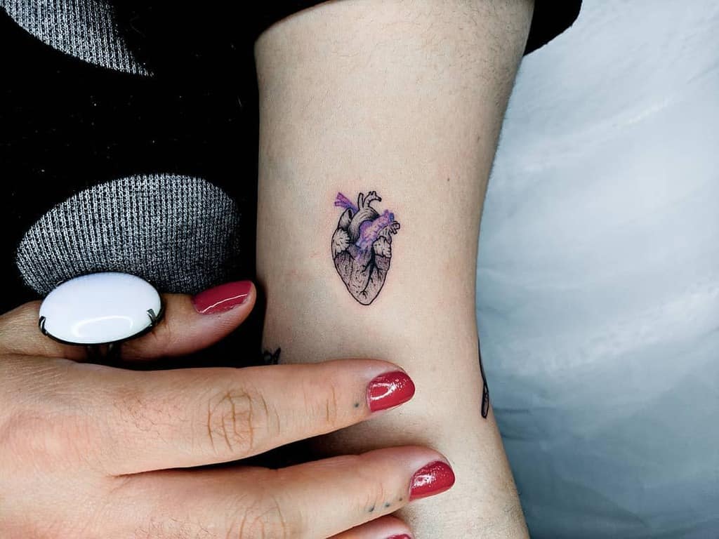 A small anatomical heart tattoo on an arm