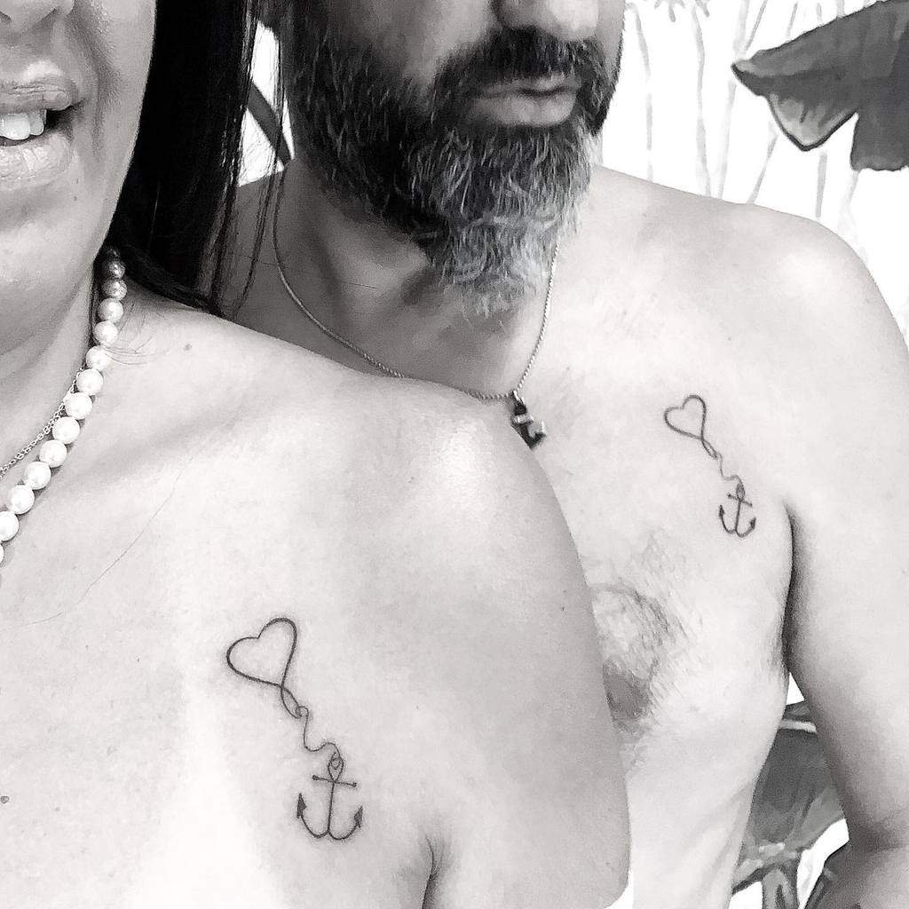 Two people with matching heart and anchor tattoos on their chests