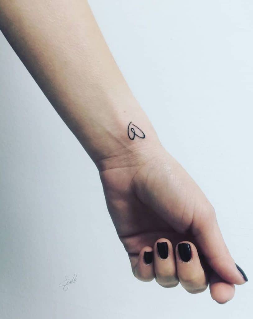 A person's wrist with a small heart tattoo