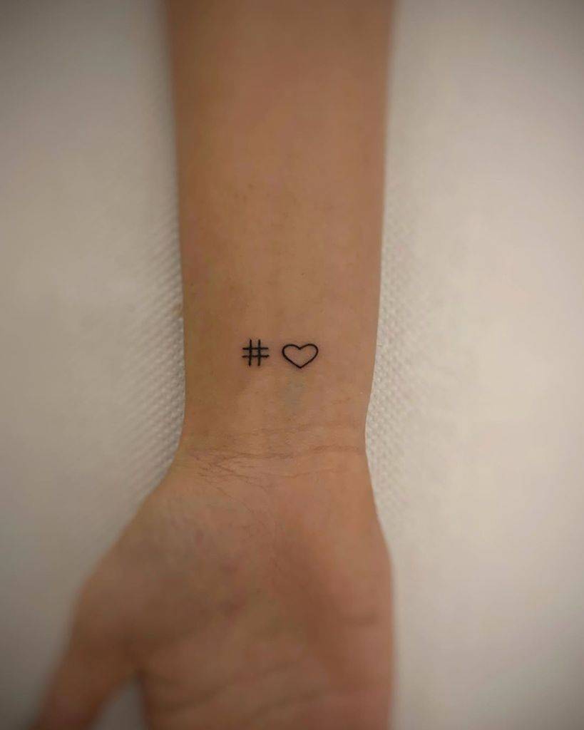 A wrist tattoo featuring a hashtag and a heart symbol