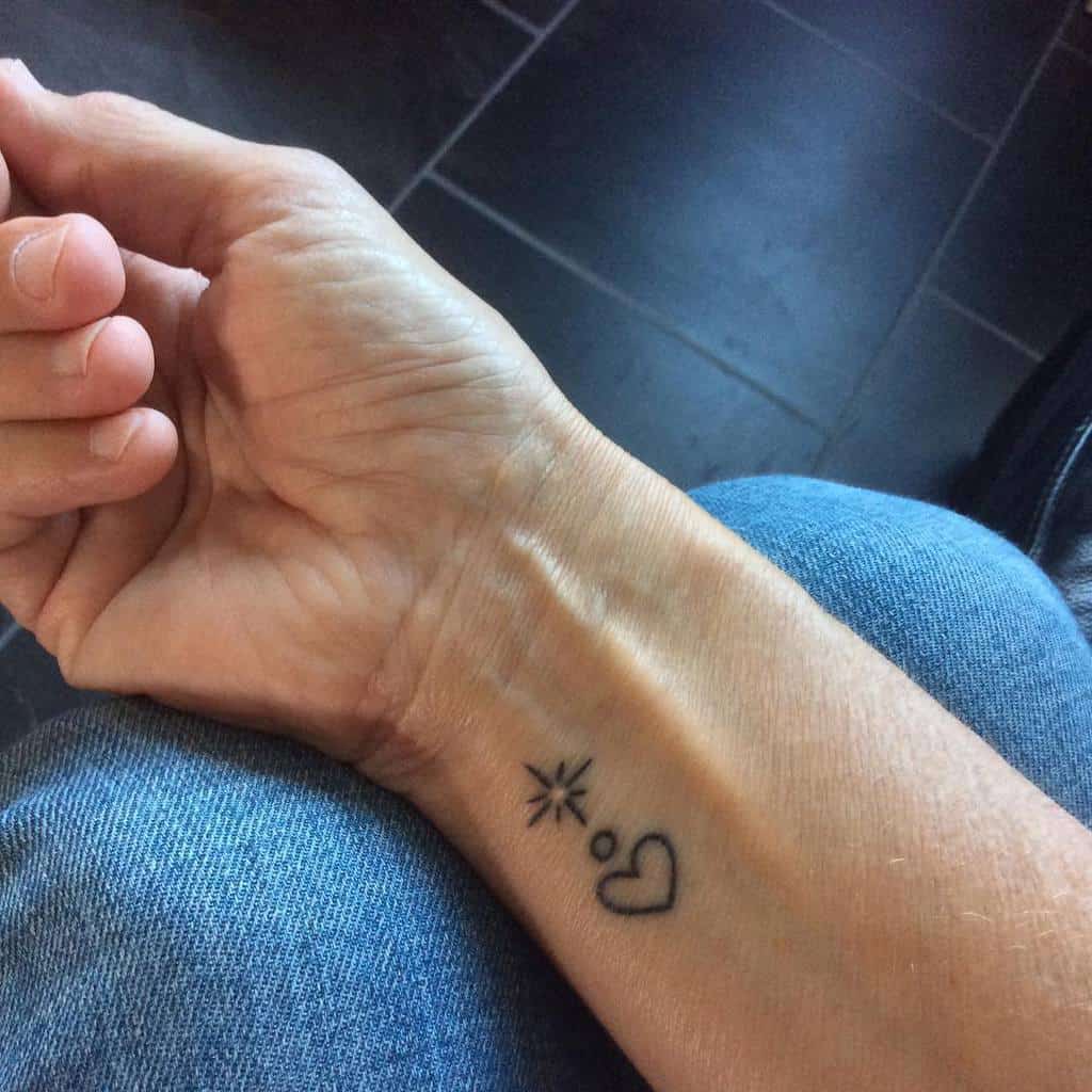 Wrist tattoo with a heart, a tiny starburst, and a small circle