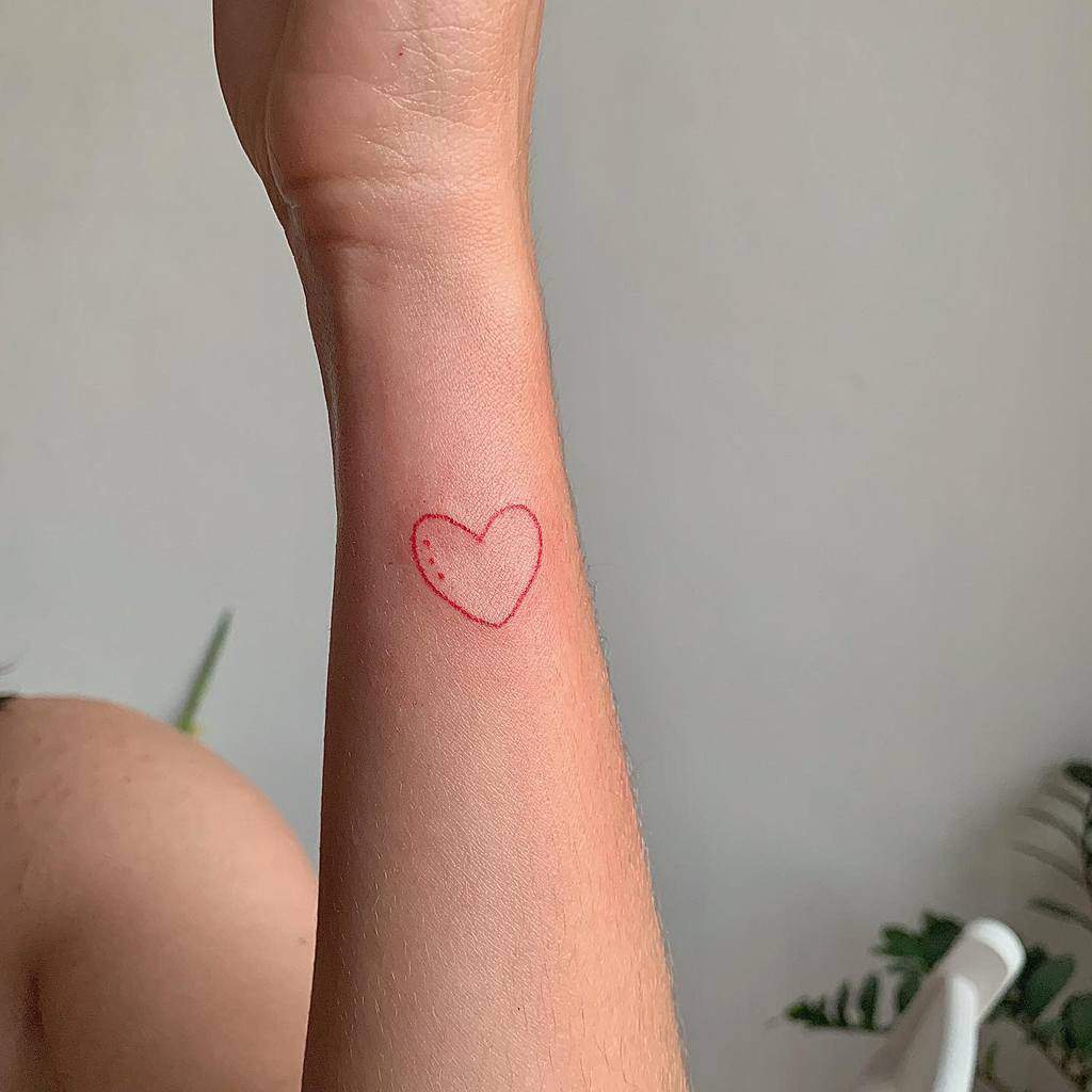 A red heart tattoo on a wrist with a minimalistic design
