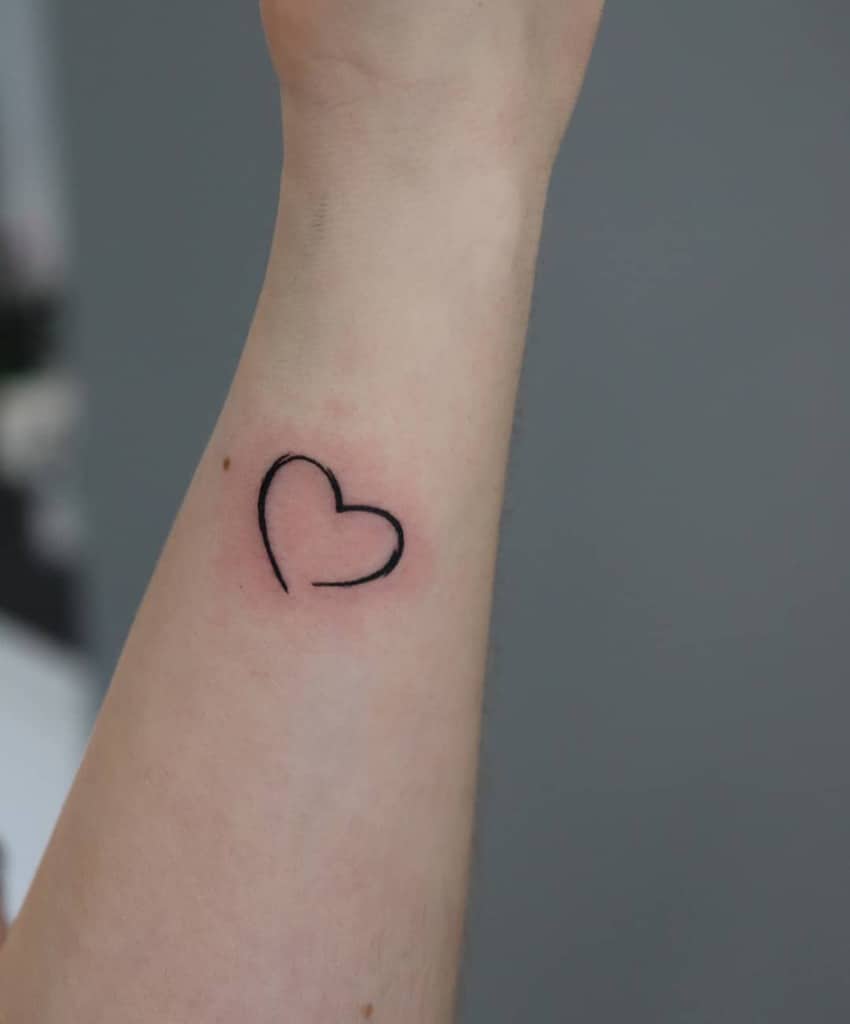 Minimalist black heart outline tattoo on a wrist