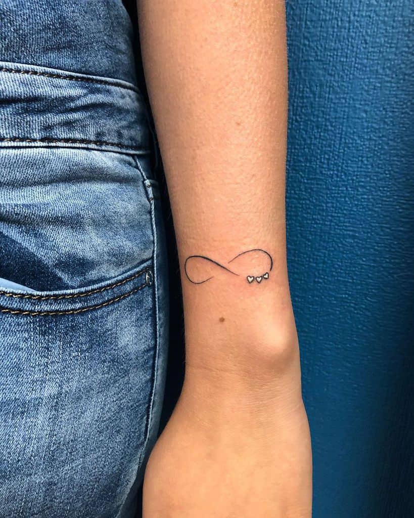Arm tattoo of an infinity symbol intertwined with three small hearts