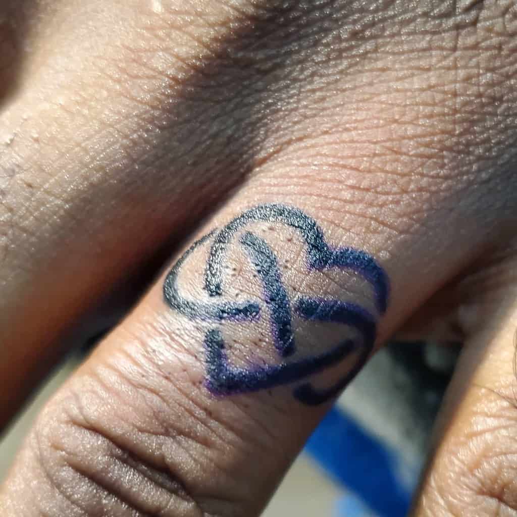 Ring finger tattoo featuring a black Celtic knot design forming a heart shape, symbolizing infinity