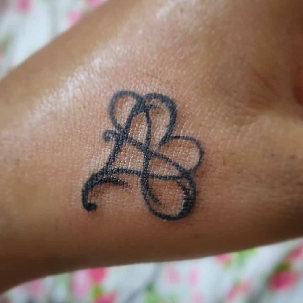 A heart-shaped tattoo intertwined with an infinity symbol, featuring a stylized cursive design