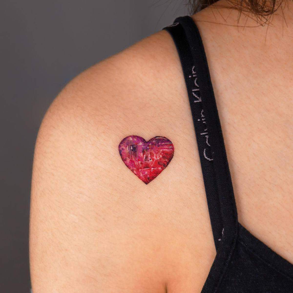 A colorful heart tattoo on a shoulder