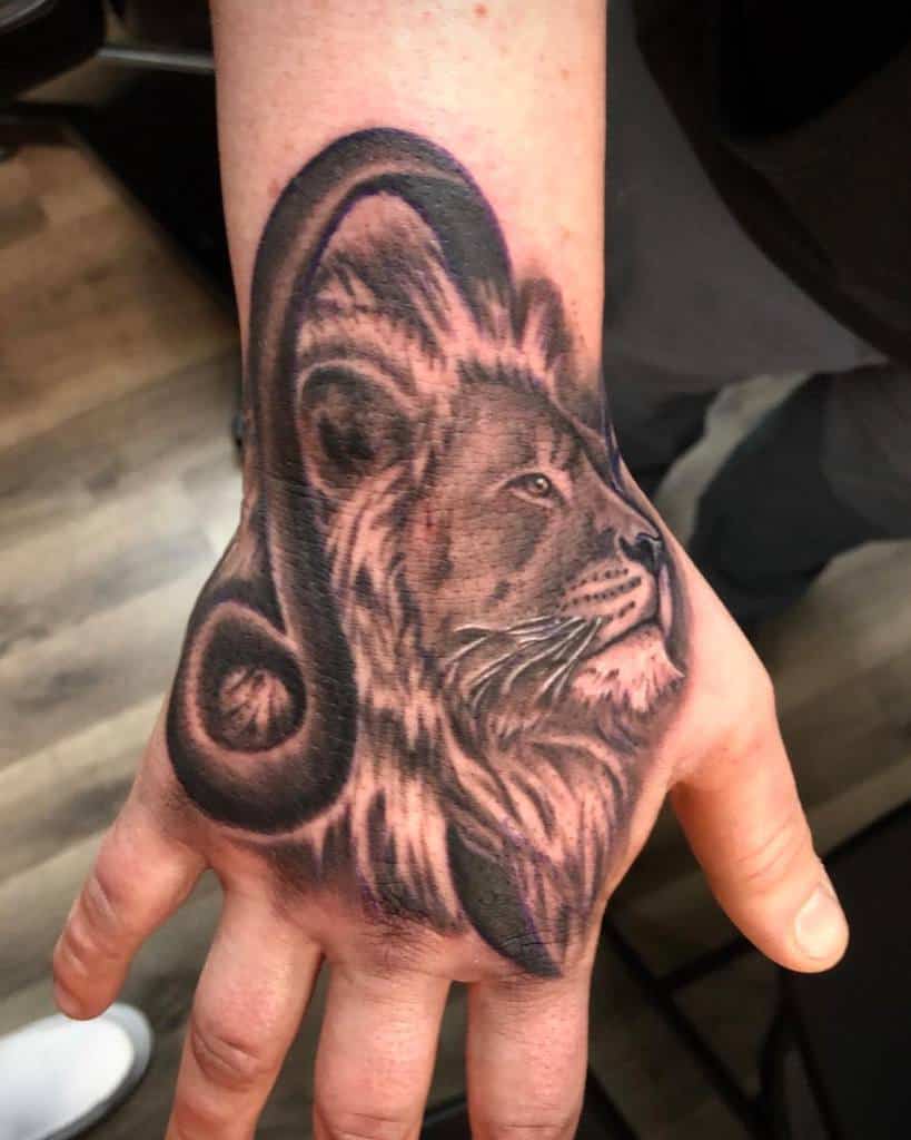 A majestic tattoo of a lion, intricately designed with a zodiac symbol, graces the hand