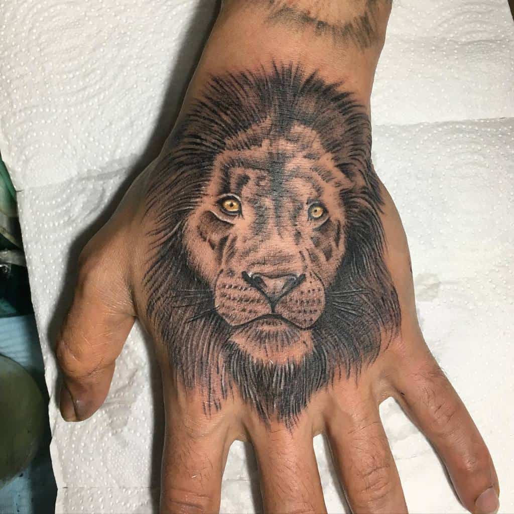A majestic lion tattoo graces the back of a hand