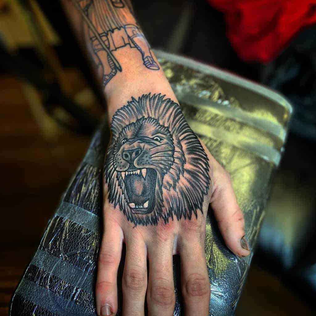 A hand adorned with a majestic lion tattoo, its fierce eyes roaring with life