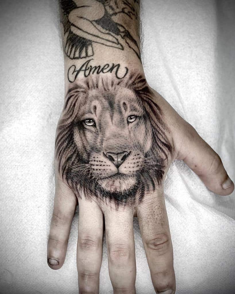 A majestic lion face tattoo graces the back of a hand, with the word "Amen" elegantly inscribed above