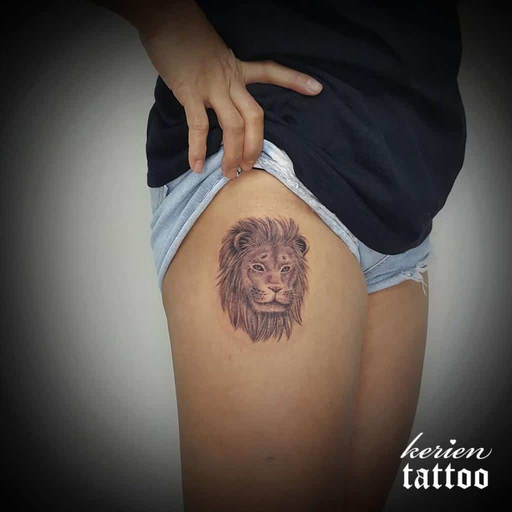 The majestic lion tattoo graces the person's upper thigh