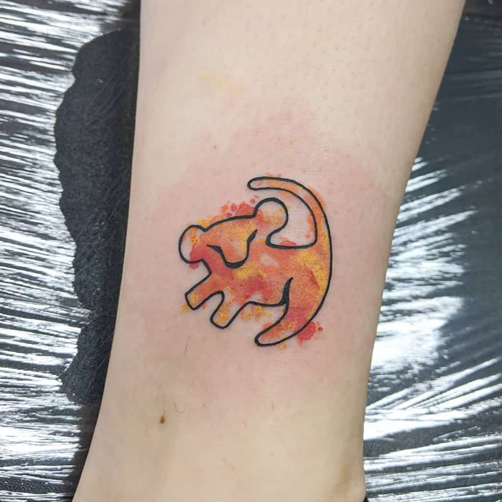A small vibrant tattoo featuring a colorful silhouette of a lion, inspired by The Lion King, with a splash of yellow and orange on the forearm