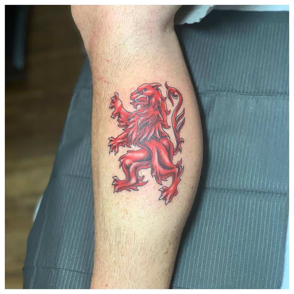 A vibrant red lion tattoo majestically adorns the back of a person's calf