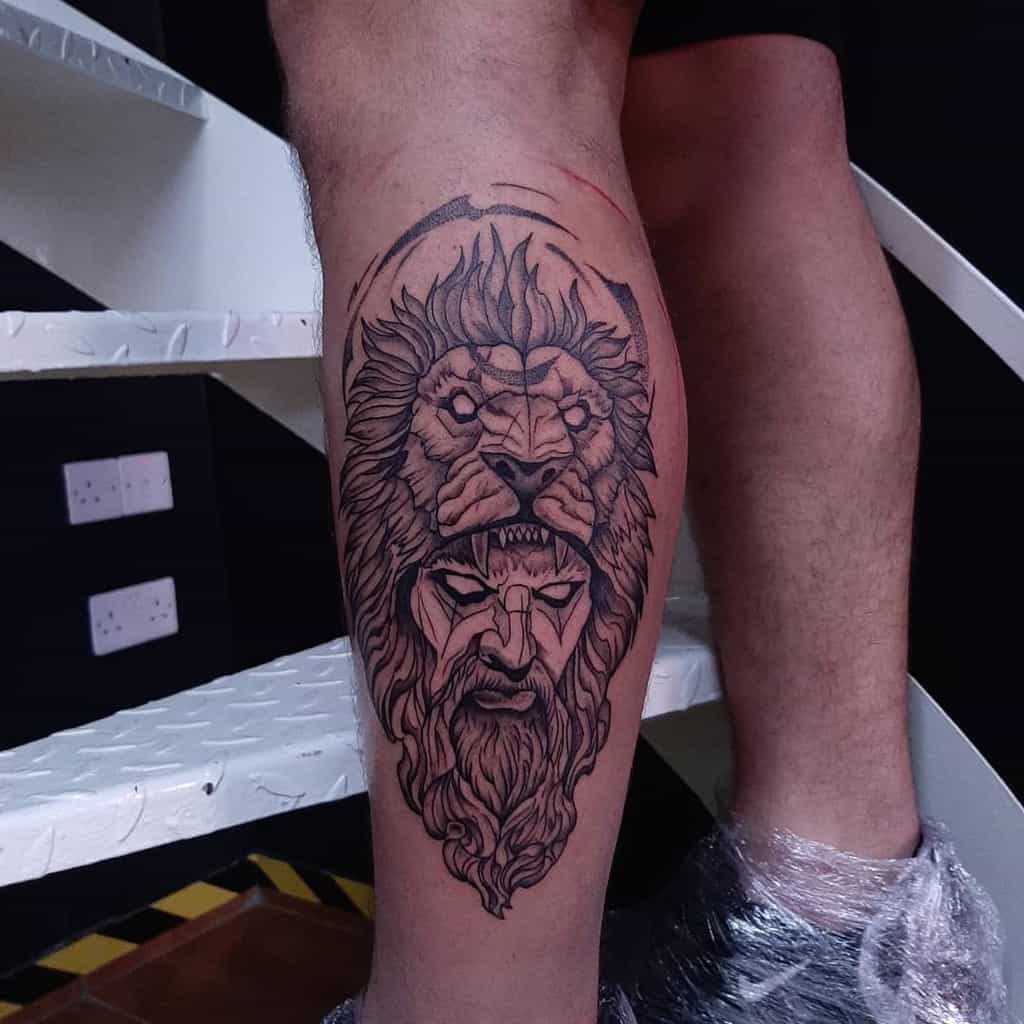 A bold black and white tattoo featuring a lion's head above a detailed human face with a beard on the leg