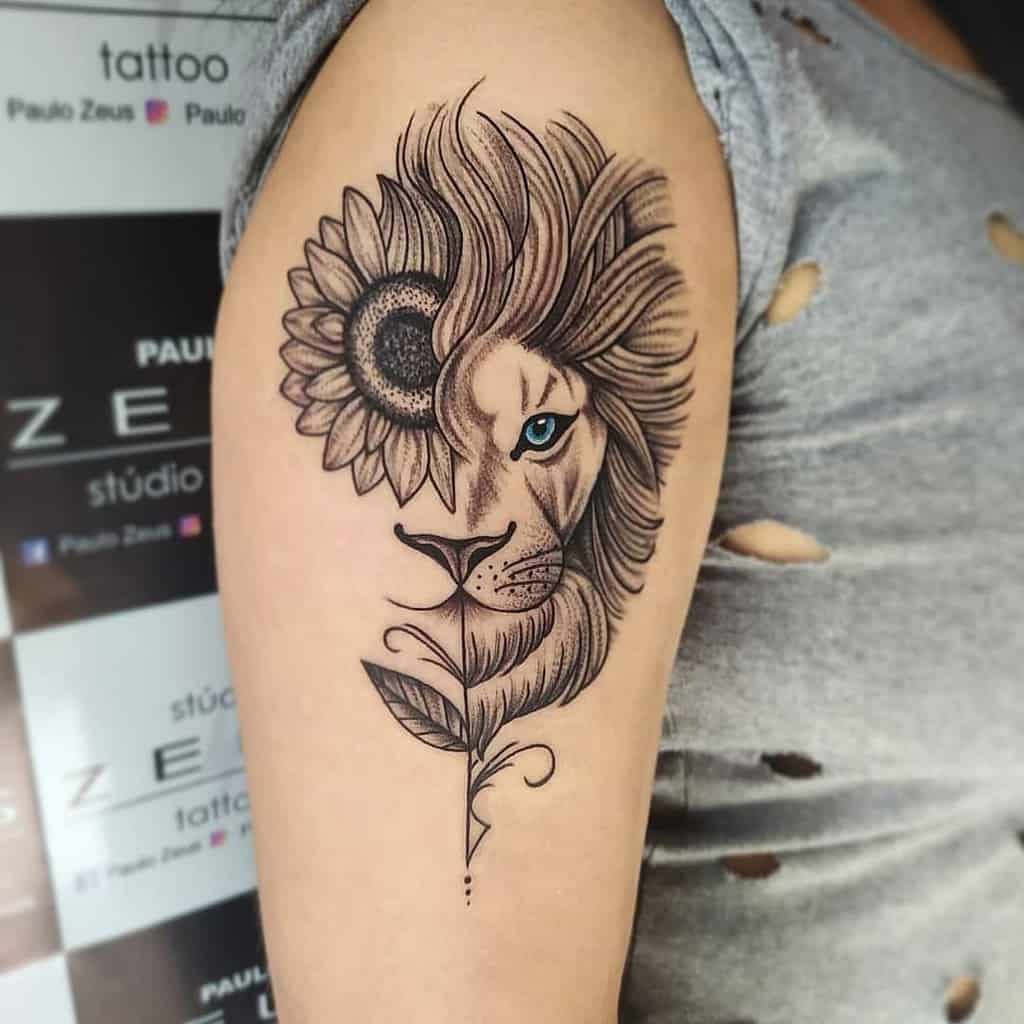 A majestic lion with vibrant blue eyes is intricately detailed alongside a sunflower on a person's upper arm, creating a striking tattoo