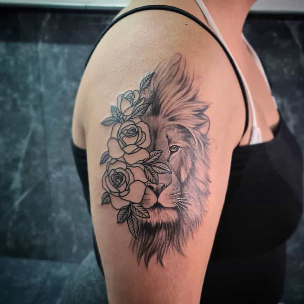 Lion and rose tattoo on the upper arm with intricate shading, featuring the majestic lion as a symbol of strength