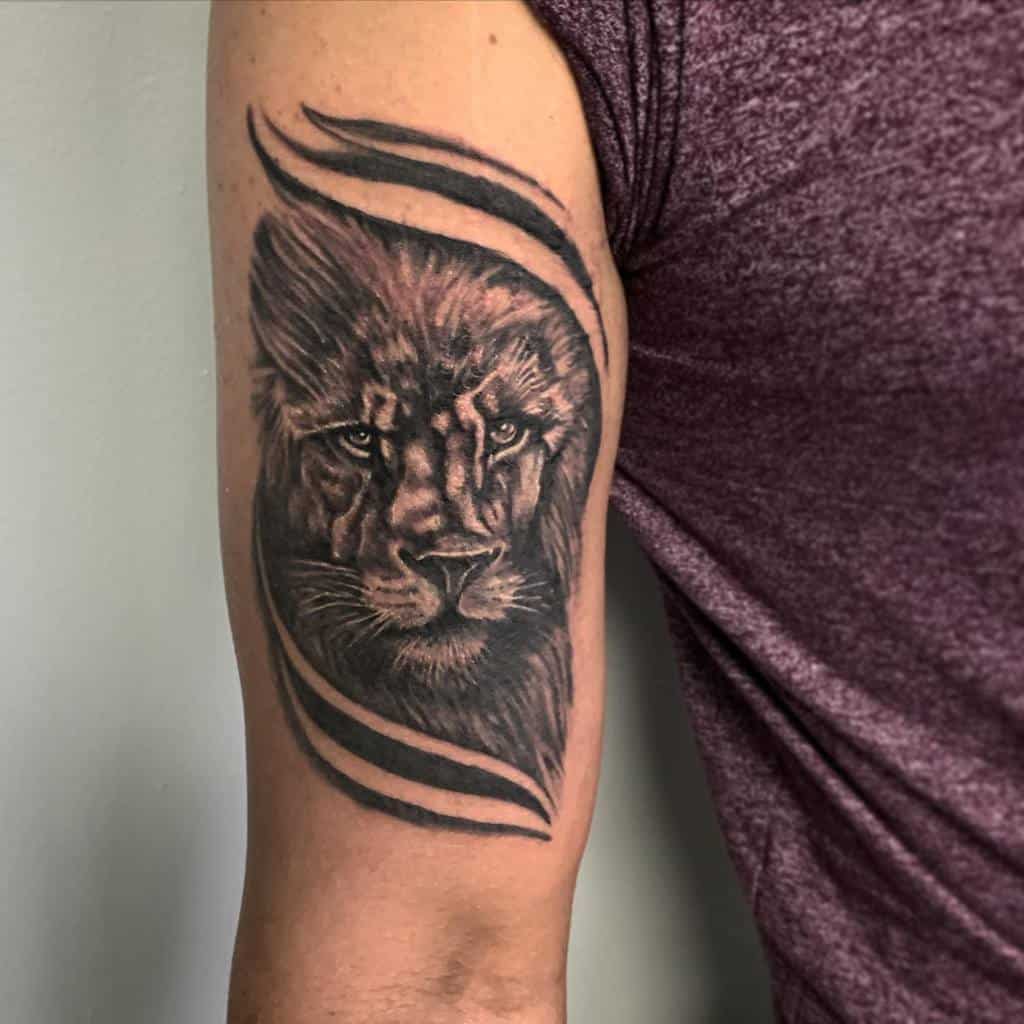Tattoo of a lion's face on a person's upper arm, surrounded by curved lines