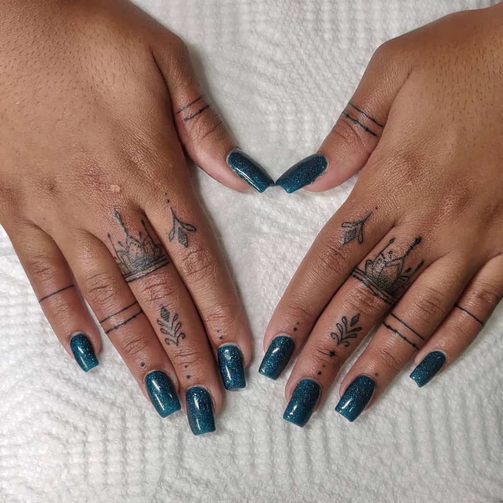 Elegant finger tattoos featuring crowns, floral accents, and minimalistic lines paired with shimmering teal nails for a regal touch