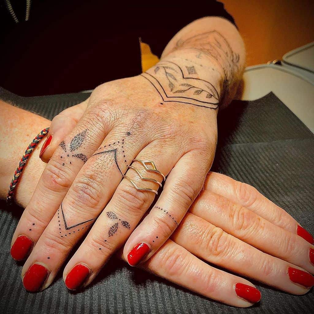 Hands with geometric mandala tattoos on fingers