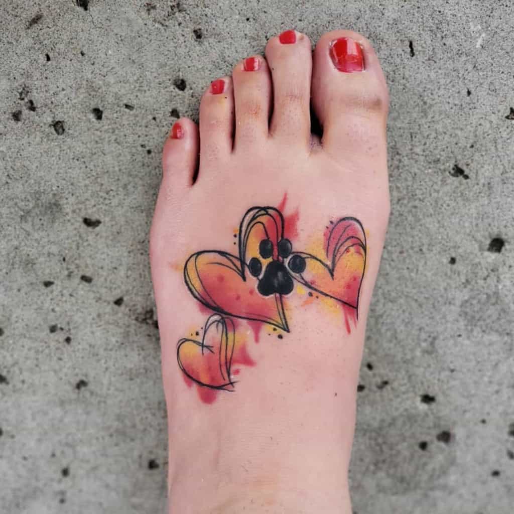 Foot tattoo featuring three hearts and a paw print in pastel colors