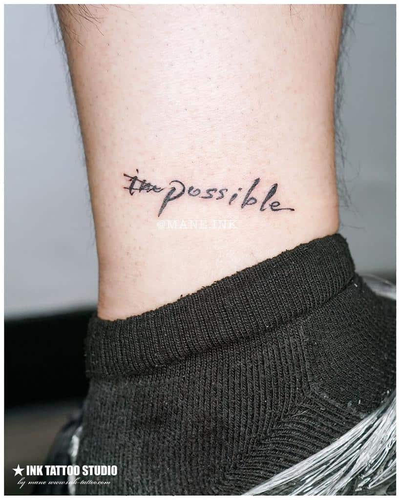 Tattoo on ankle reads "impossible" with "im" crossed out, transforming the word into "possible"