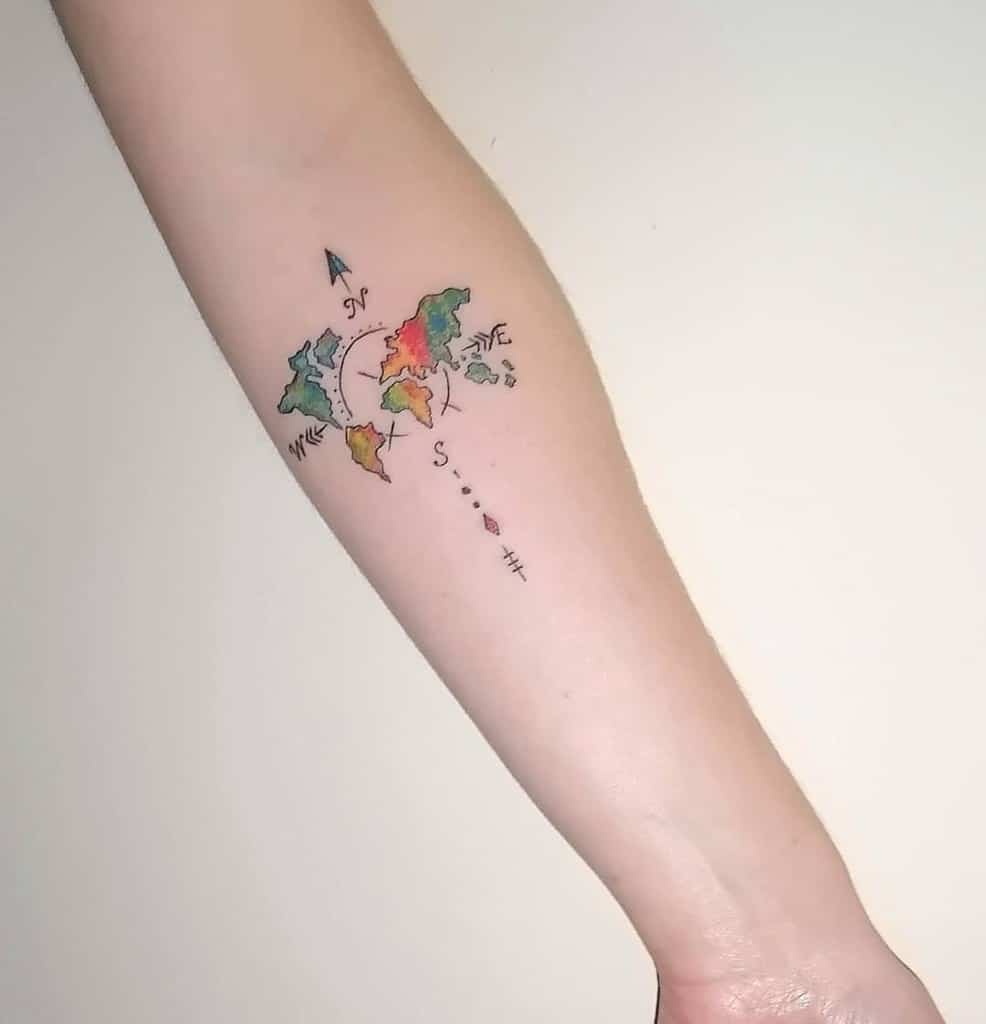 A tattoo of a colorful world map with compass arrows on a forearm