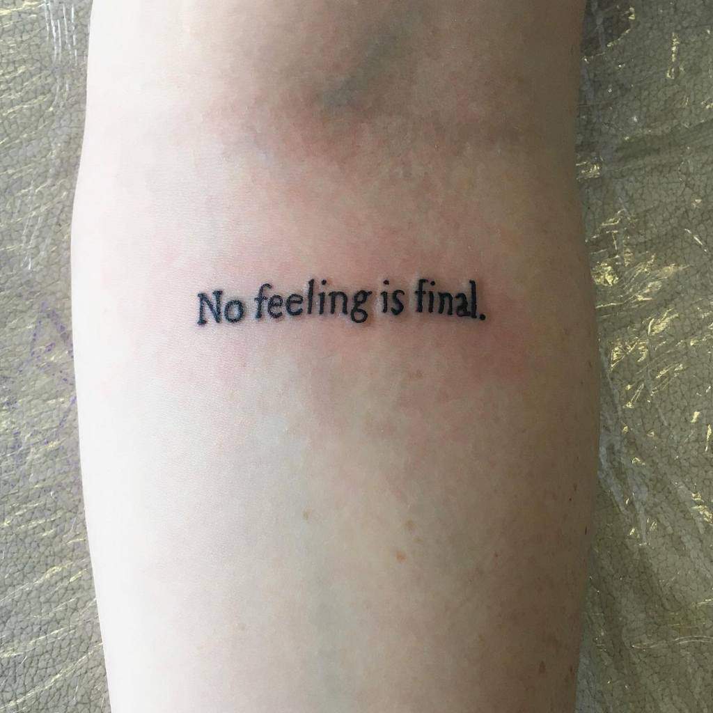 Minimalist forearm tattoo with the phrase 'No feeling is final' in simple black font'