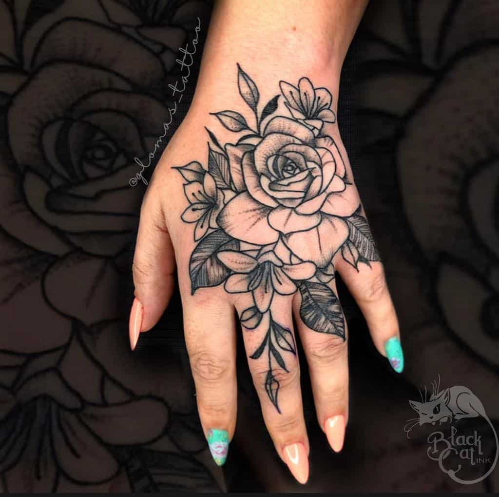 Hand with a black rose tattoo and floral design