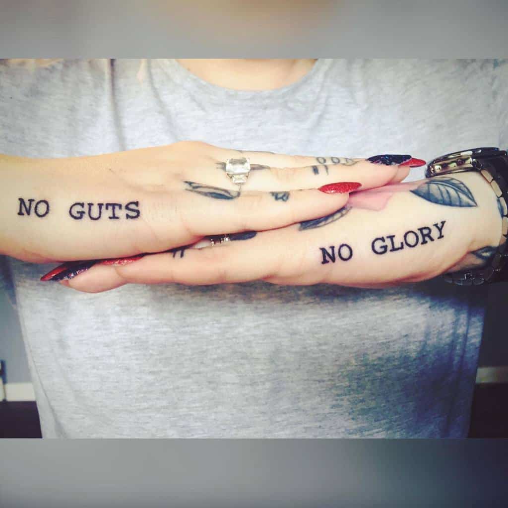 Hands with tattoos saying "NO GUTS" on one and "NO GLORY" on the other