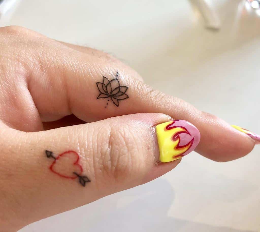 Minimal finger tattoos featuring a black lotus flower and a red heart with an arrow
