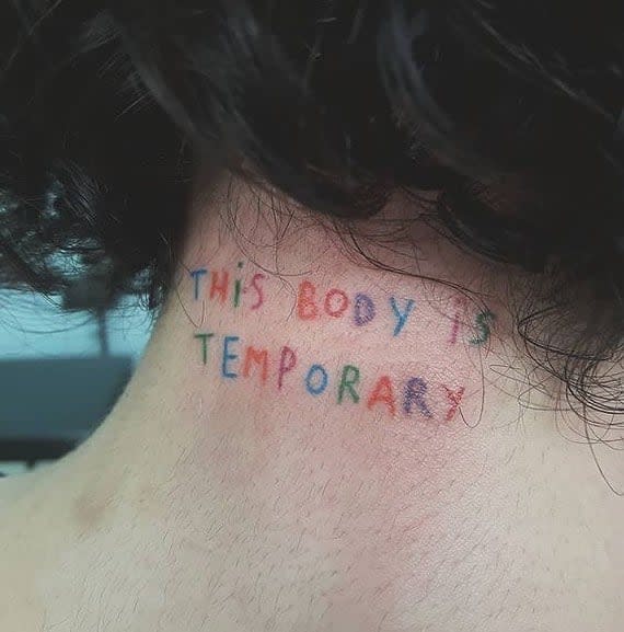 Colorful tattoo on a person's neck reads "THIS BODY IS TEMPORARY" with a small red heart