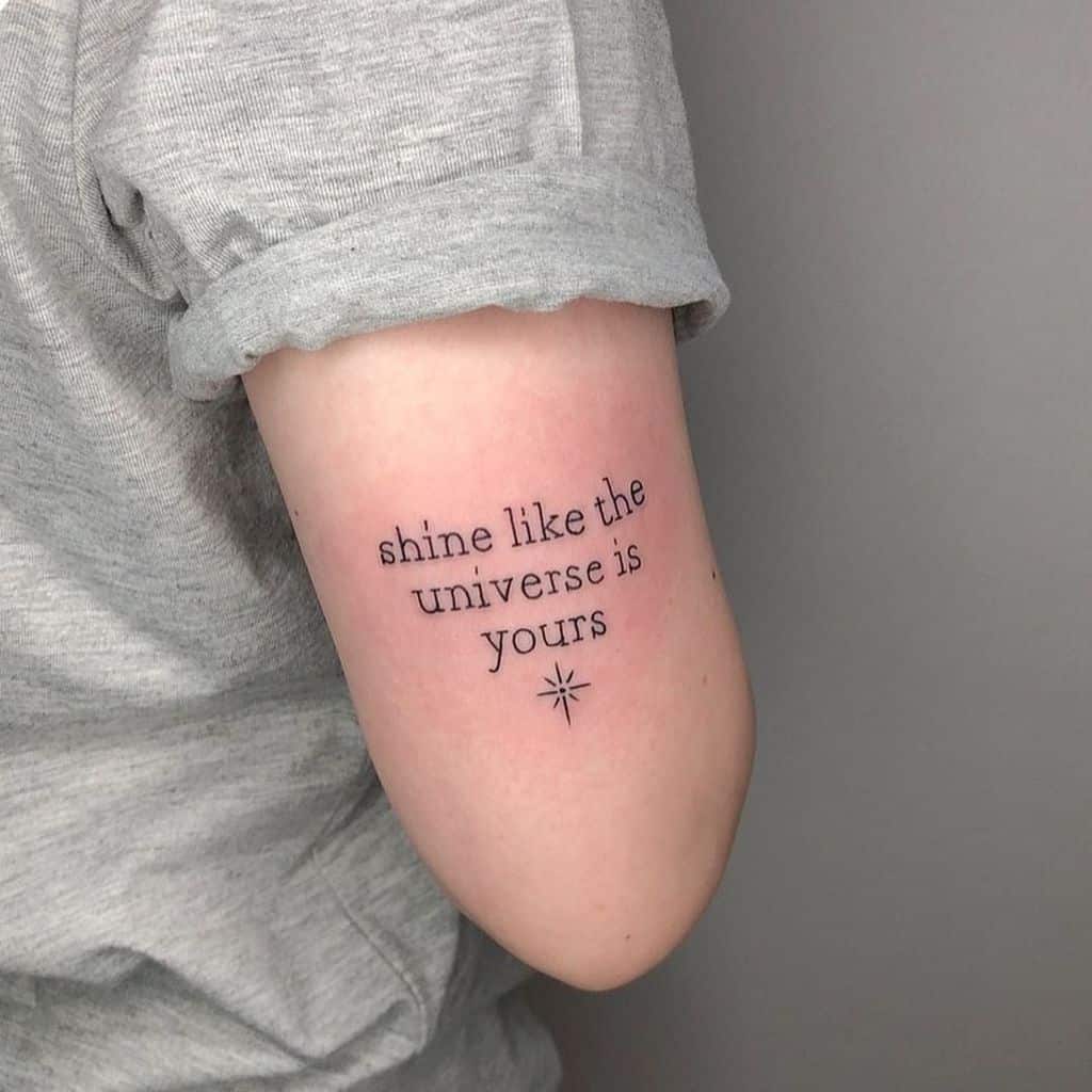 Text tattoo on arm saying "shine like the universe is yours" with a small star symbol below