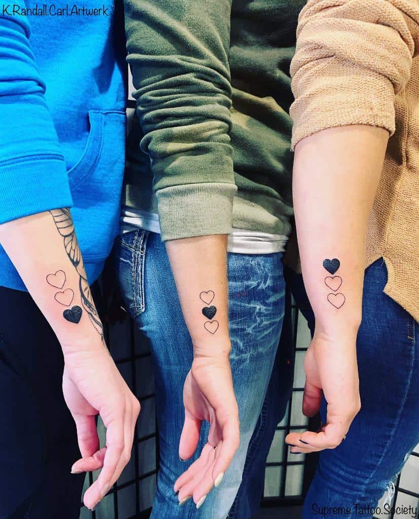 Three forearms with matching tattoos of three hearts, each heart shaded differently, in a vertical row
