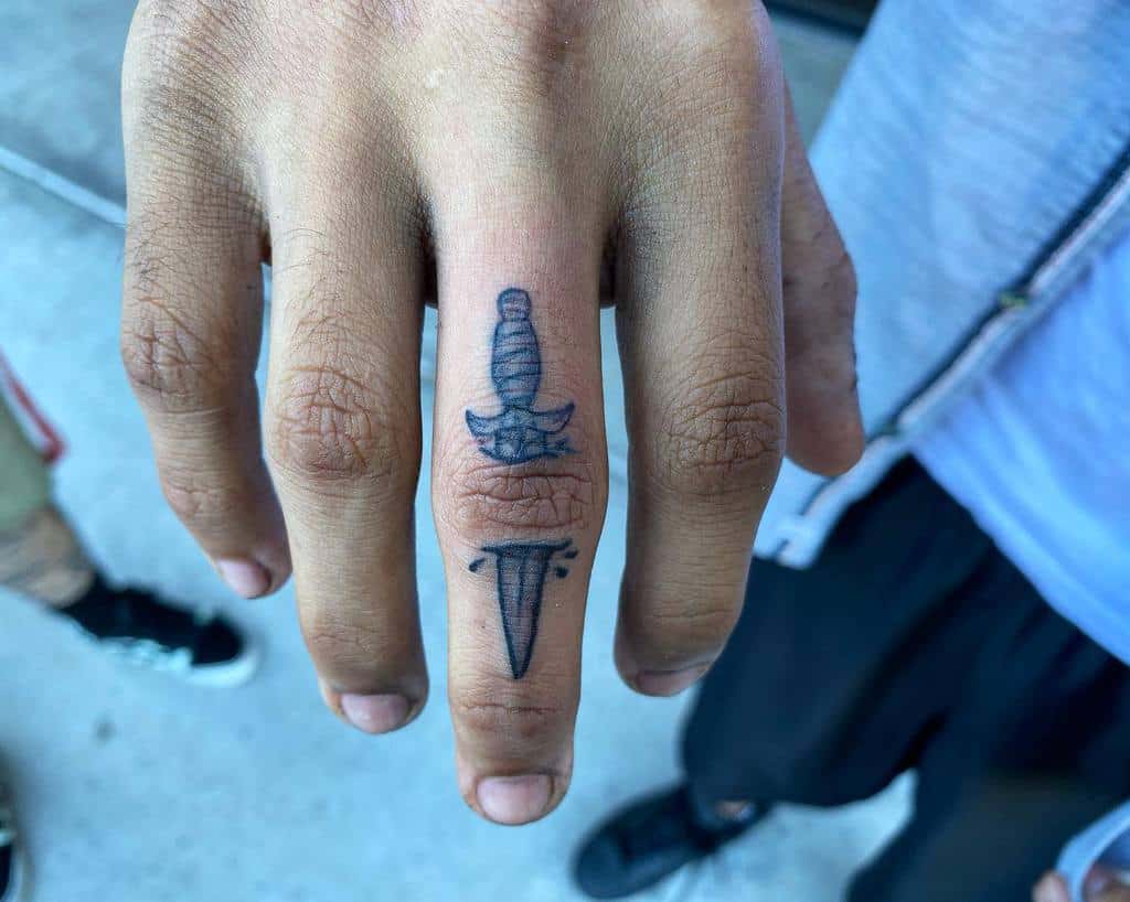 Hand with a dagger tattoo on the middle finger
