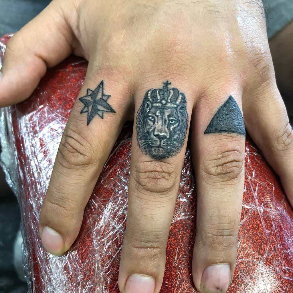 Hand with tattoos of a star, a crowned lion, and a triangle on the fingers