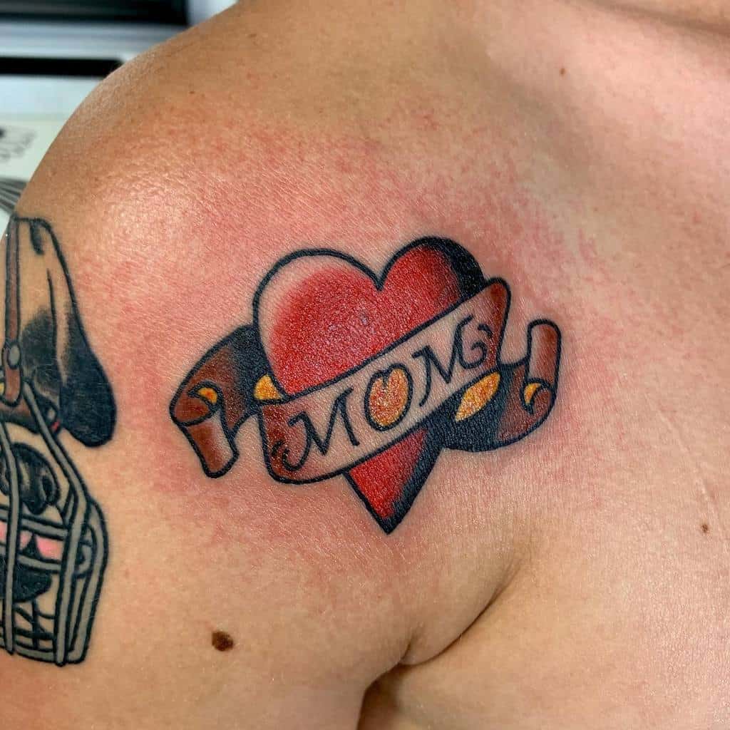 Heart tattoo on the shoulder with a ribbon that reads "MOM," encapsulating love and tribute