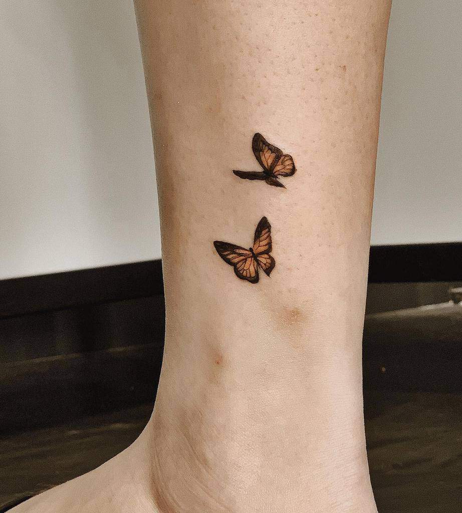 Two small, black and orange monarch butterfly tattoos on an ankle