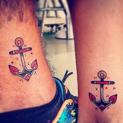 Matching navy anchor tattoos with colorful details on ankles
