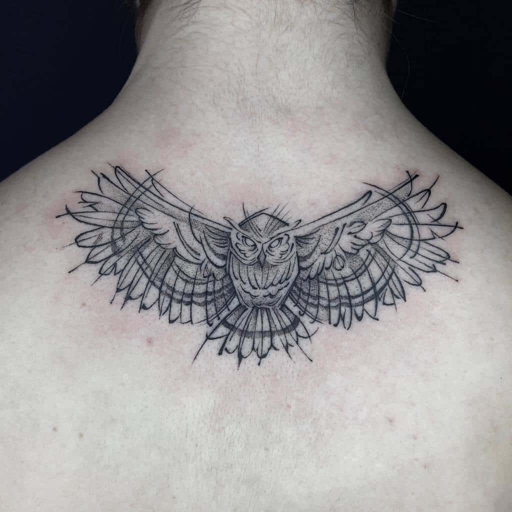 A mesmerizing line art tattoo featuring an owl with majestic, outstretched wings elegantly adorns the upper back