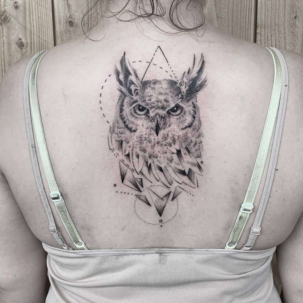 Tattoo of an owl with geometric shapes on a woman's upper back