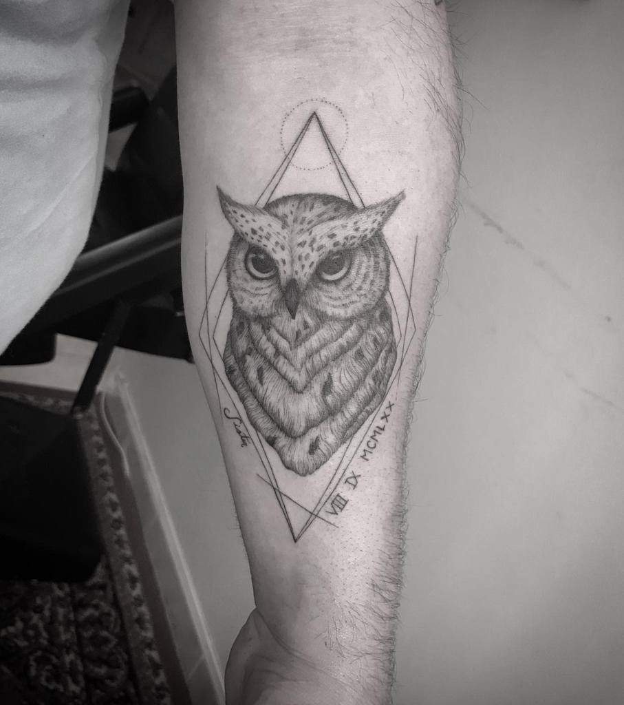 An intricately designed owl tattoo with geometric shapes adorns a person's forearm, showcasing a harmonious blend of nature and modern art
