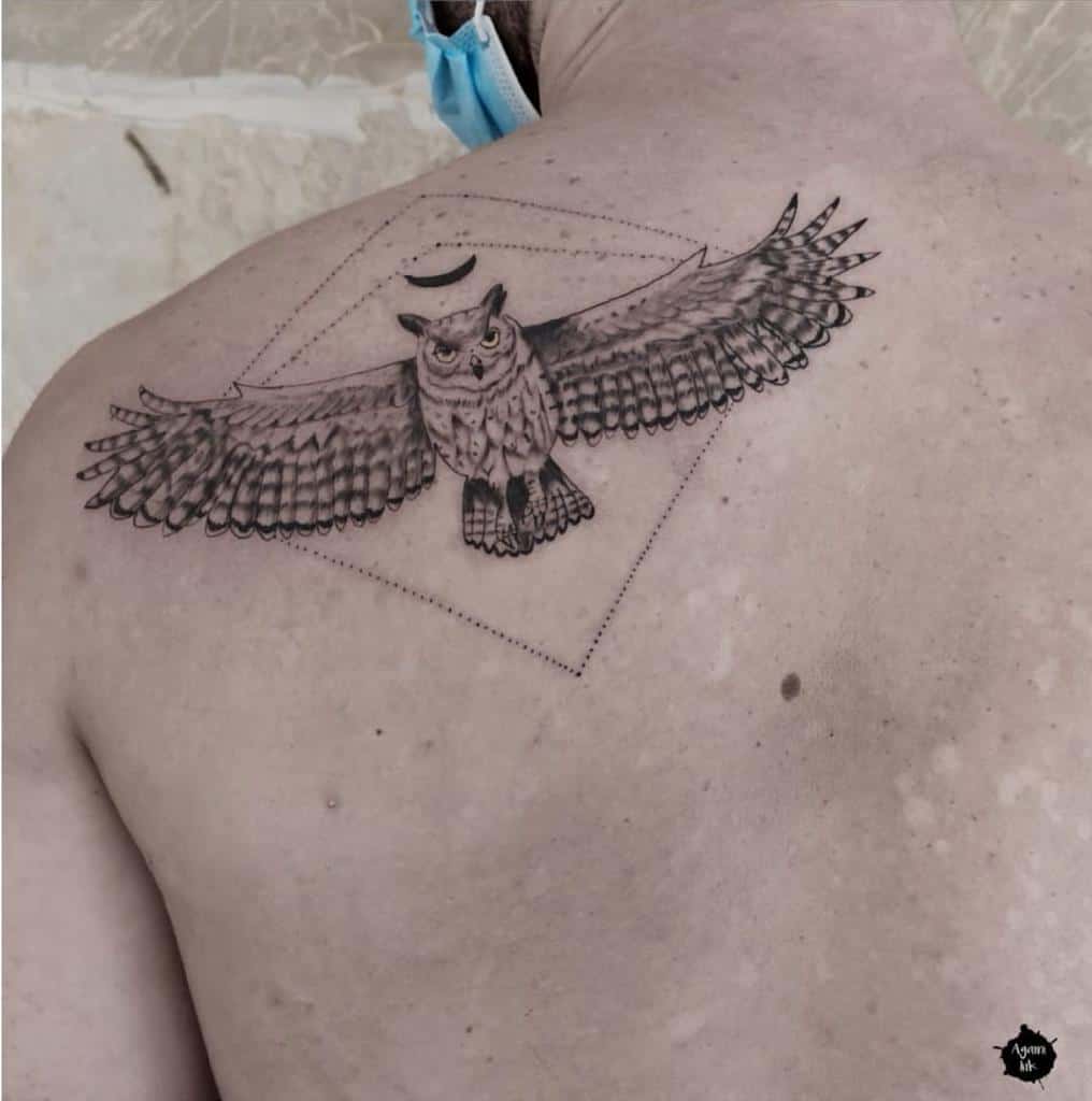 Tattoo of an owl with majestic, outstretched wings on an upper back