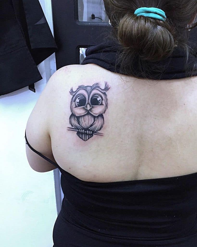 A cute, cartoonish owl tattoo on the shoulder, with large expressive eyes and a playful expression, adding charm to the design