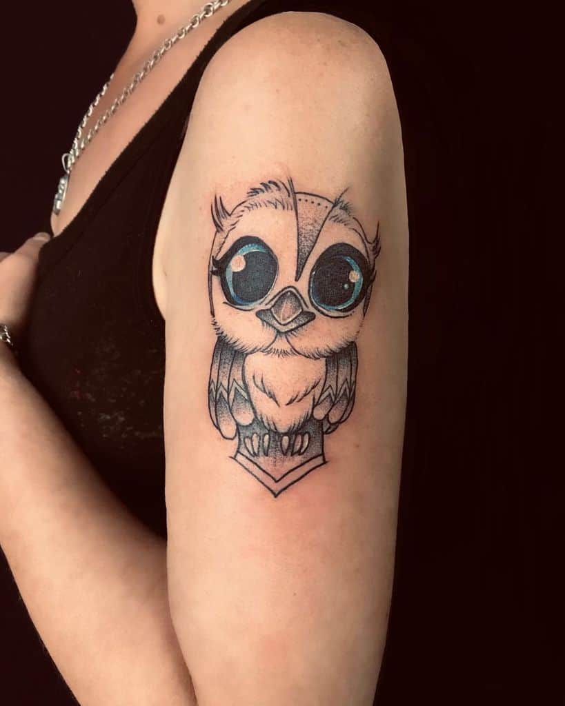 Tattoo of a cute owl with big eyes on an upper arm